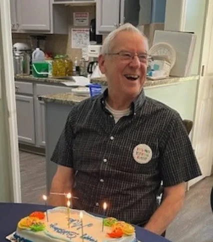 A Century Assisted Living resident laughing while celebrating his birthday with cake